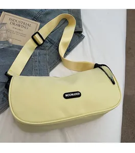 Detail view of the yellow crescent bag with wide nylon strap and black brand logo label