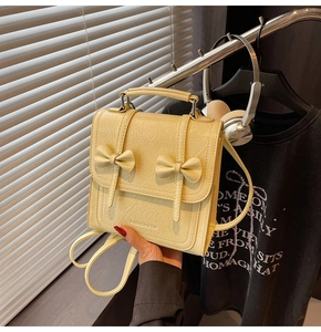 Detail of cream backpack with crinkle leather texture and elegant decorative bows
