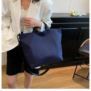 Detail of navy blue nylon tote bag showing wide black straps and detachable shoulder belt