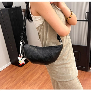Detail of black crescent bag with lychee texture and a cute white chick pendant