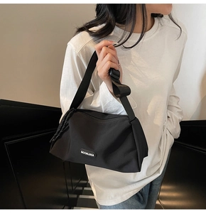 Gros plan du sac bandoulière noir montrant la sangle réglable et le logo de la marque