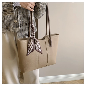 Detail of light brown tote bag with premium pebbled texture and silk scarf handle accent