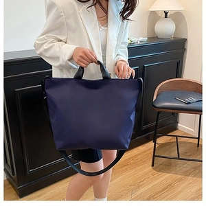 Detail of navy blue nylon tote bag with reinforced corners and black sturdy handles
