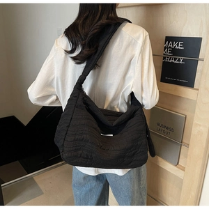 Detail of black quilted tote bag shoulder strap and textured fabric shown on model