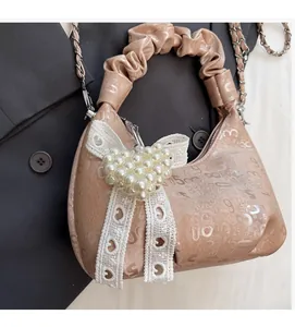 Detail of light brown PU bag with embossed patterns and pearl heart bow accessory