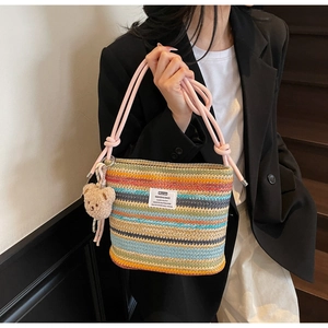 Detail of colorful rainbow woven straw tote bag with pink rope handle and plush bear charm