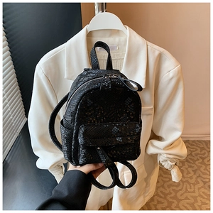 Close-up of black faux leather backpack featuring trendy python skin texture and top handle