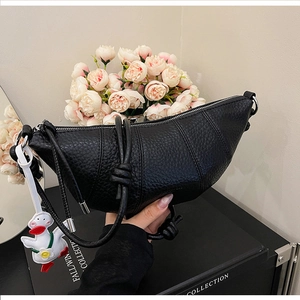 Detailed macro view of black lychee grain leather croissant bag with knotted handle detail