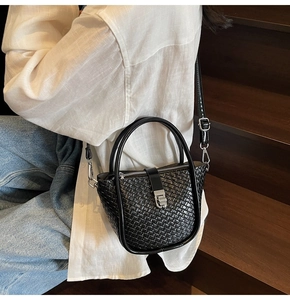 Detailed view of black woven texture leather bucket bag with silver hardware accents