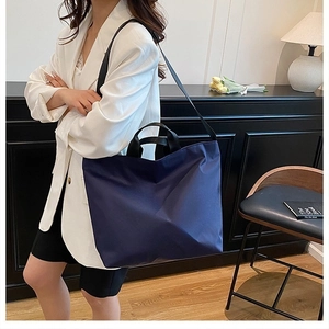 Navy blue large nylon tote bag shown in a professional lifestyle shot for urban commuting