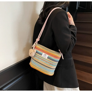 Detail of colorful woven straw bucket bag with pink rope strap and plush bear charm