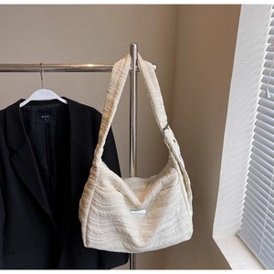 Detail of beige quilted shoulder bag showing wavy stitching and adjustable wide strap