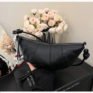 Detail of black croissant bag with quilted leather texture and cute duck charm pendant