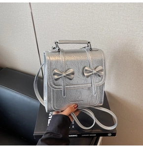 Detail of silver crinkled texture mini backpack with twin bows and metal finish
