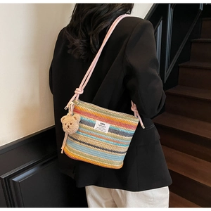 Close-up of rainbow striped woven bucket bag with cute bear charm and pink strap