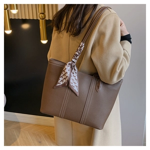 Brown leather tote bag detail with lychee texture and houndscotth silk scarf on handle