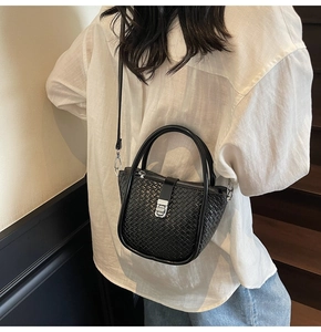 Detailed shot of black woven bucket bag texture with silver clasp and top handles
