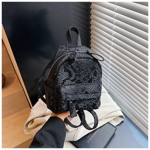 Detailed view of mini black snakeskin backpack featuring silver zippers and top handle