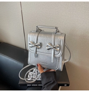 Detail of silver metallic mini backpack with wrinkled texture and stylish twin bow accents
