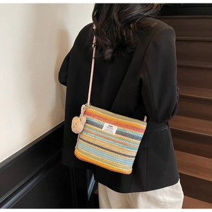 Detail of woven straw bucket bag with colorful stripes and cute bear pendant accessory