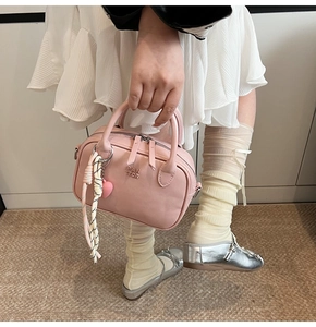 Détail d'un sac à main en cuir rose avec pendentif tressé et décoration en cœur