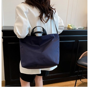 Detail view of a large navy blue tote bag shown on model for size and style reference