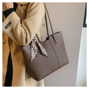 Detail of lychee pattern leather tote bag with white contrast stitching and silk scarf