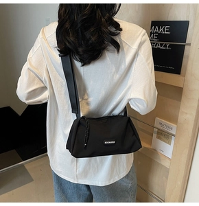 Vue mannequin d'un sac bandoulière noir en nylon avec large sangle et logo rond
