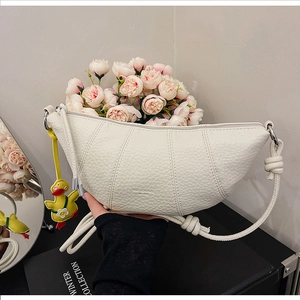 Detail of white moon bag with litchi texture, duck pendant and soft studio lighting