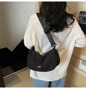 Detail view of the black crescent crossbody bag with mooners logo and adjustable strap