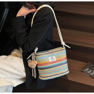 Rainbow striped woven bucket bag featuring white rope straps and brown plush bear charm