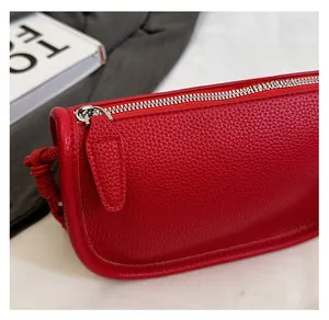 Gros plan sur la fermeture éclair argentée et le cuir rouge grainé du sac bandoulière