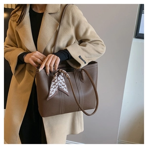 Detail of lychee pattern leather tote bag with white contrast stitching and silk scarf decoration