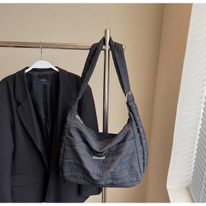 Detail of black quilted shoulder bag with silver hardware and ripple texture