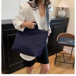 Navy blue tote bag shown on a model in a stylish office or home workspace setup