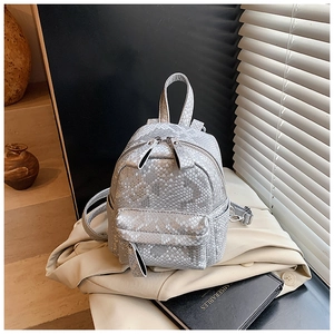 Detail of silver snake-pattern mini backpack with dual zippers and metallic texture