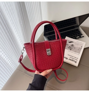 Detail view of red woven texture handbag with silver metal buckle and sleek zip closure