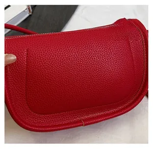 Gros plan détaillé du sac selle en cuir rouge grainé avec coutures régulières