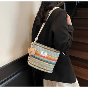 Detail of colorful striped woven bucket bag with rope strap and cute bear charm