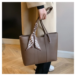 Detail of dark brown tote bag with contrast stitching and hounds-tooth scarf handle