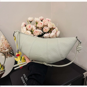 Detail of light green crescent bag showing lychee grain texture and knot strap