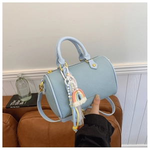 Detail of light blue pebble leather boston bag with rainbow tassel and golden hardware