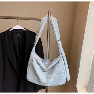Detail showing light blue quilted puff fabric texture and strap metal ring on shoulder bag