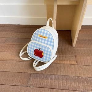 Dettaglio dello zaino a scacchi con patch a mela rossa e ricamo dello slogan Not Anxious