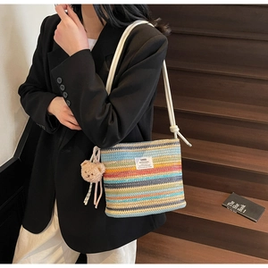 Detail of colorful striped woven bucket bag with rope strap and teddy bear charm