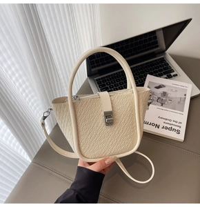 Detail of cream woven pattern bucket bag with metal buckle and shoulder strap in a lifestyle setting