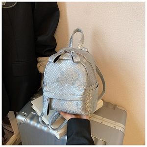 Detail shot of silver mini backpack with snakeskin texture and double zippers on the suitcase