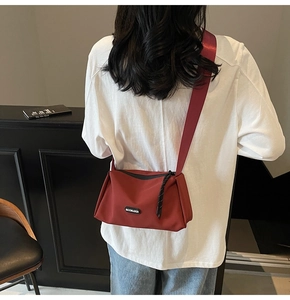 Détail du sac bandoulière vintage rouge en toile avec large sangle porté par un mannequin