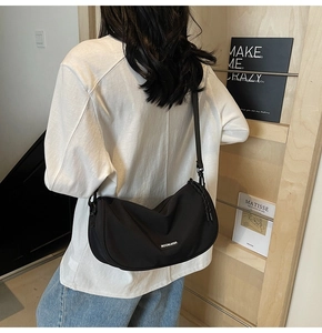 Back view of model wearing black nylon crescent crossbody bag with adjustable strap