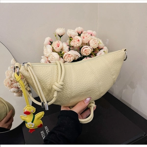 Detail of beige lychee leather croissant bag with knotted strap and yellow duck charm